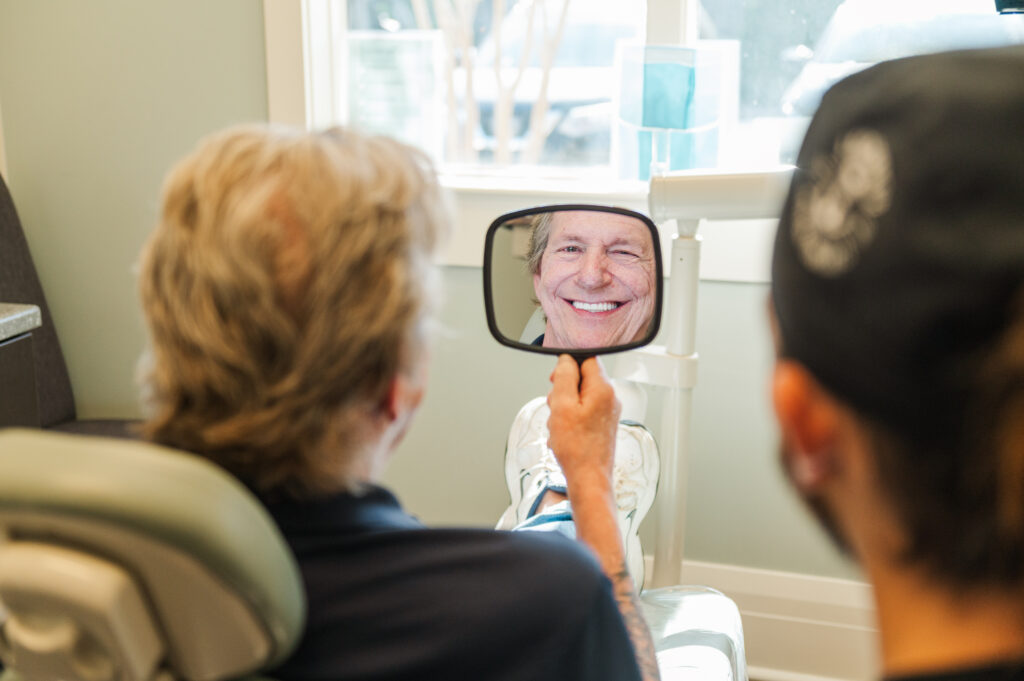 Patient smiling into mirror with new all-on-x dental implants